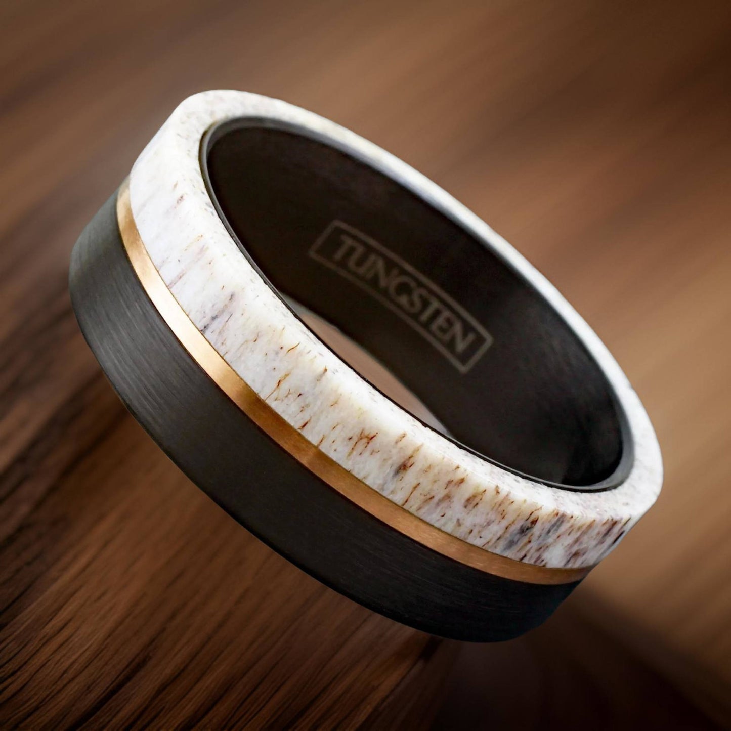 polished black ring made of military grade tungsten, deer antler, and rose gold